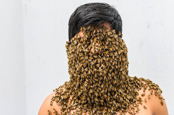 Beekeeper covered by bees, he has the queen bee on his neck so all the bees stick to his body. surrealism.