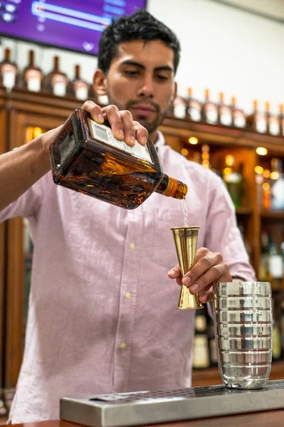 Bartender está adicionando ingrediente em shaker no balcão de bar . — Fotografia de Stock