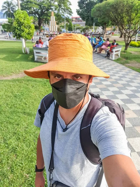Retrato de um turista com uma máscara médica, mochila e câmera tirando uma selfie com um celular. — Fotografia de Stock