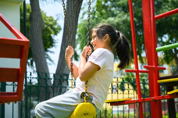 Happy little hispanic girl child having fun to playing in the park in summer time with smile and laughing healthy, Adorable girl having fun on a swing on summer. happy vacation lifestyle concept. — Foto Stock