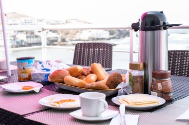 Plaj manzaralı ahşap bir masada kahvaltı. Kahvaltıda deniz manzaralı yumurtalı ekmek. Kahvaltı için harika bir yer.