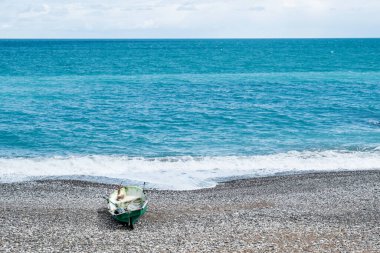 Deniz kıyısı, gökyüzü ve dalgalar. Sahilde insansız bir tekne var. Balıkçı teknesi, deniz kenarında yaşam.