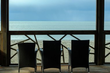 Deniz kıyısındaki verandada üç boş sandalye. Hayır millet, sezon bitti. Terkedilmiş tatil köyü