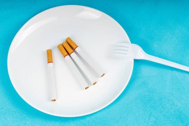 Tabakta dört sigara ve tek kullanımlık plastik bir çatal. Yemek yemek, nikotin bağımlılığıyla savaşmak yerine