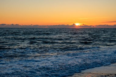 Günbatımında soğuk sonbahar denizi ve gökyüzü. Denizde gün sona eriyor. Akşamları denizde