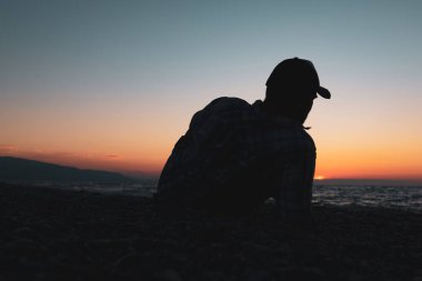 Deniz kıyısında uzanan ve dinlenen bir adamın silueti. Kıyı şeridi ve insan