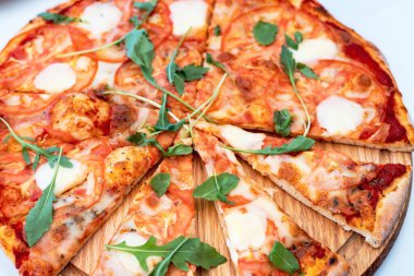 Dilimlenmiş pizzayı, yuvarlak ahşap bir stantta yakın plan çekime alın. Taze otlu ev yapımı pizza.