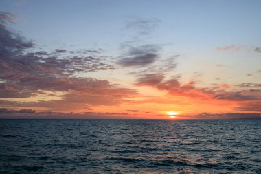 Akşam denizde, güneş ve bulutlar gökyüzünde batıyor. Gün batımında deniz manzarası