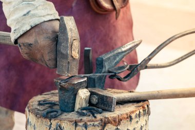 Bir demircinin elinde çekiç ve maşa, bir demircinin yakın plan çalışması tarihi bir eğlence. Rusya 'da bir panayırda.
