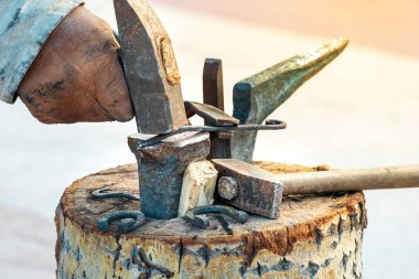 Bir demircinin eli çekiçle küçük bir örse çivi çakar. Ortaçağ demirciliğinin taklidi