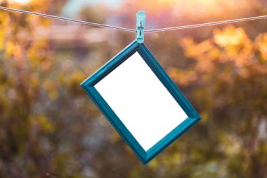 Mavi ahşap çerçeve yatay olarak gerilmiş bir ipe asılı. Yazıtlar olmadan fotoğraf için boş çerçeve