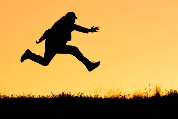 Силуэт Человека Шляпе Бегущего Прыгающего Оранжевом Фоне Бег Проблем Людей — стоковое фото