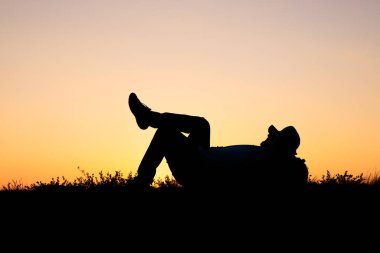 Adamın silueti bacağında bacağıyla yerde yatıyordu. Rahatlamış insan dinleniyor. Doğada rahat.