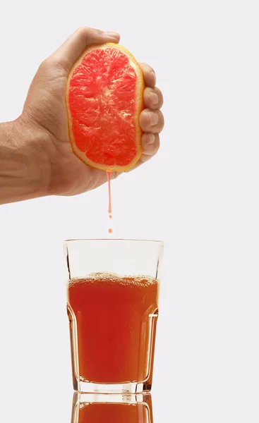 Glass of grapefruit juice and hand with half of grapefruit