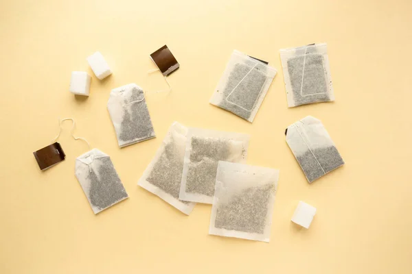 Colocação plana de vários sacos de chá no fundo bege, vista superior — Fotografia de Stock