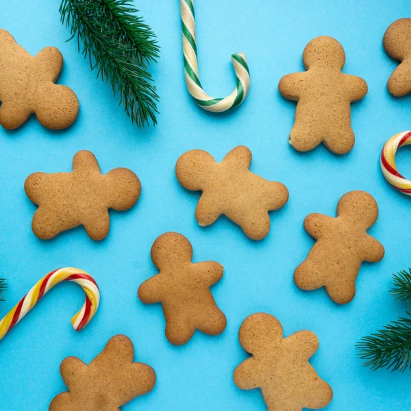 Різдвяне імбирне печиво у формі чоловіка з льодяниками та ялиновими гілками на синьому фоні, вид зверху — стокове фото