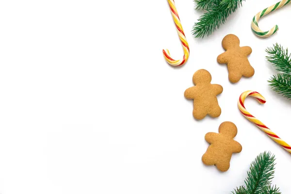 คุกกี้ขนมปังขิงคริสต์มาสในรูปร่างของผู้ชายที่มีอมยิ้มและกิ่งก้านฟางบนพื้นหลังสีขาว พื้นที่สําหรับข้อความ — ภาพถ่ายสต็อก