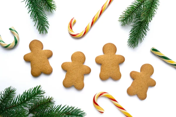 पांढरा पार्श्वभूमीवर ललिपॉप्स आणि फायर शाखा असलेल्या मनुष्याच्या आकारात ख्रिसमस जिंगरब्रेड कुकीज, शीर्ष दृश्य — स्टॉक फोटो, इमेज