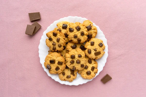 분홍색 직물 배경에 초콜릿 칩을 얹은 홈 메이드 쿠키, 맨 위 뷰 — 스톡 사진
