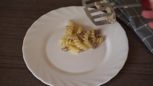 Vrouw hand zet fusilli pasta met vlees op bord — Stockvideo