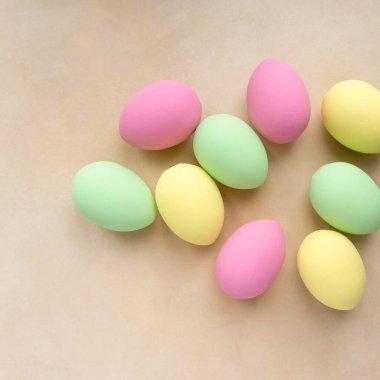 Paskalya düzlüğü. Bej arkaplanda pastel renklerle boyanmış yumurtalar, üst görünüm