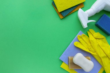 Flat lay of various cleaning products and items on green background, space for text