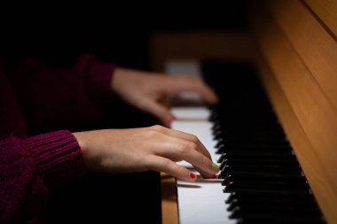 Piyano çalan renkli tırnaklı bir kızın elleri.