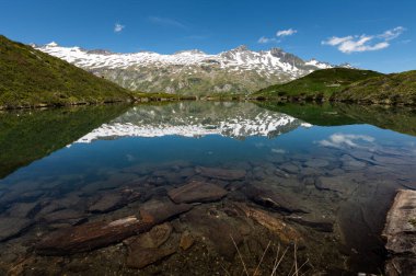 Grossvenediger yakınlarındaki Avusturya Alplerinde küçük bir gölet, yazın güneşli bir gün, karlı dağların yansıması