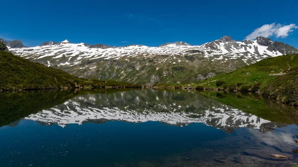 奥地利阿尔卑斯山中的一个小池塘 靠近格鲁斯维迪格尔 夏日阳光灿烂 映衬着雪山 — 图库照片