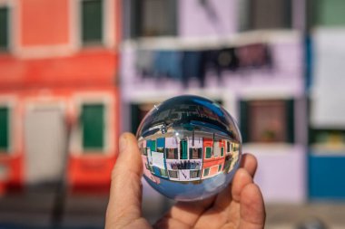 Burano, Venedik 'te (İtalya) renkli evlerin önünde el ele tutuşan cam küre, sonbaharın sonlarında güneşli bir gün