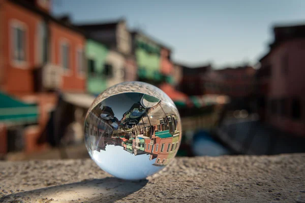 stock image Glass ball lying on pillar in front of colorful houses in Burano, Venice (Italy), sunny day in late