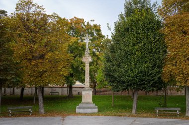 Votivkreuz 17. yüzyılda taştan yapılmış, Viyana 'da Augarten Park, sonbaharda bulutlu bir gün, renkli yapraklar.