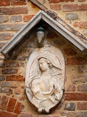 Venedik 'te (İtalya) mermerden yapılmış bir azizin portresi, tuğla duvar, sonbaharda bulutlu bir günde açık havada.