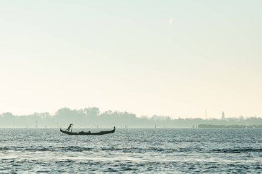 Venedik, İtalya - 29 Ekim 2021: İnsanoğlu güneşli bir kış gününde Venedik (İtalya) gölünde gondolda kürek çekiyor