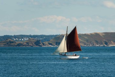 Perros-Guirec, Fransa - 24 Ağustos 2020: Perros Guirec yakınlarındaki eski yelkenli, koyu kırmızı yelkenli, güneşli gün