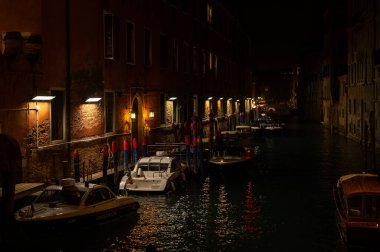 Venedik, İtalya - 31 Ekim 2021: Sonbaharda tekneli Kanal, sudaki sokak lambalarının yansıması