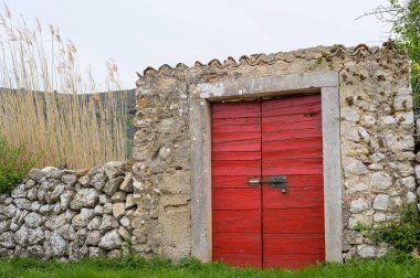 Taze kırmızı ahşap kapılı taş duvar, Cres (Hırvatistan)