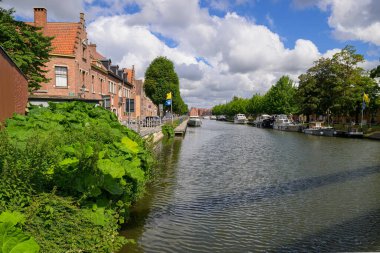 Brugge, Belgium - July 4, 2022: Old canal with trees and houses in Bruges