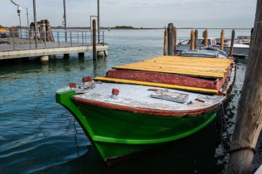 Venice, Italy - October 26, 2021: Green boat in Burano on a sunny day in autumn, no people