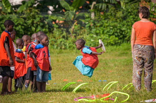 乌干达 卡兰加拉 2022年5月19日 孩子们在草地上和来自欧洲的人玩耍 多云的一天 女孩跳起来 — 图库照片