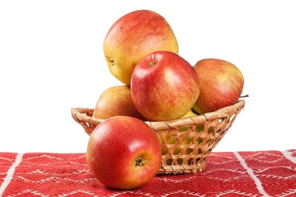 Manzanas rojas en canasta de mimbre sobre mantel rojo —  Fotos de Stock