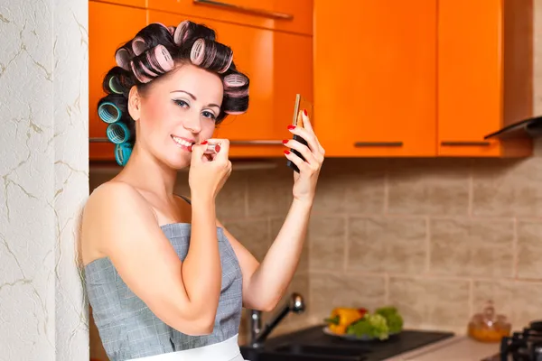 Kobiet gospodyni średnim wieku maluje usta w kuchni — Zdjęcie stockowe
