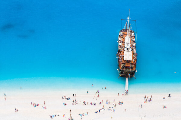 Large sail cruise ship anchored at white sand beach