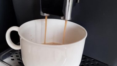 Yüksek köpüklü sıcak kokulu siyah kahve kahve kahve makinesinden beyaz renkli büyük bir fincana dökülüyor. 4k Video