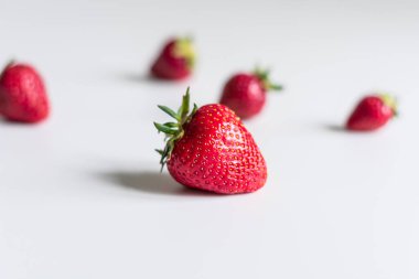 Hafif arka planda çilekli yakın plan. Arka planda güçlü bir çözünürlükte çilek var.