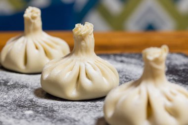 Khinkali usulü Gürcistan usulü hamur köftesi, tahtadan yapılmış un, siyah arka plan. Khinkali pişirme süreci.