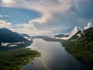 Bulutların ve dağların üzerindeki güzel panoramik manzara. Ortasında güneş yükseliyor..