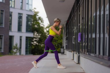 Lastik bantlı genç bir bayan şehirde egzersiz yapıyor..