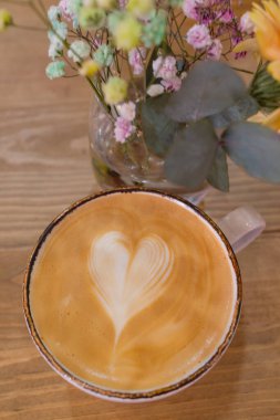 cappucino kalp şekli köpüklü beyaz tabak kaşık ile üzerinde.