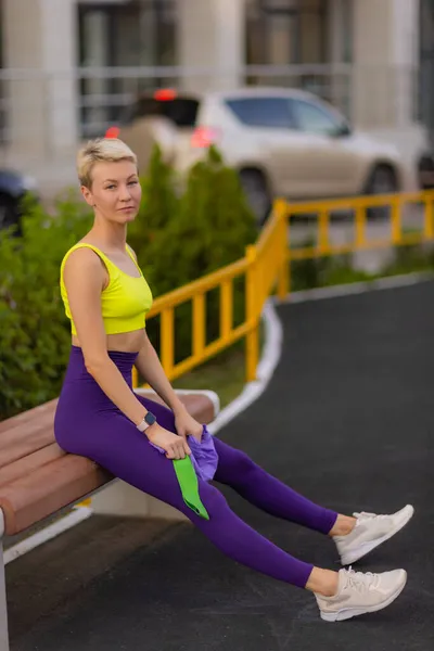 En ung idrottskvinna med elastiskt band som tränar utomhus i stan. — Stockfoto